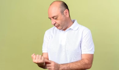 Задумчивый мужчина смотрит на кожу запястья
